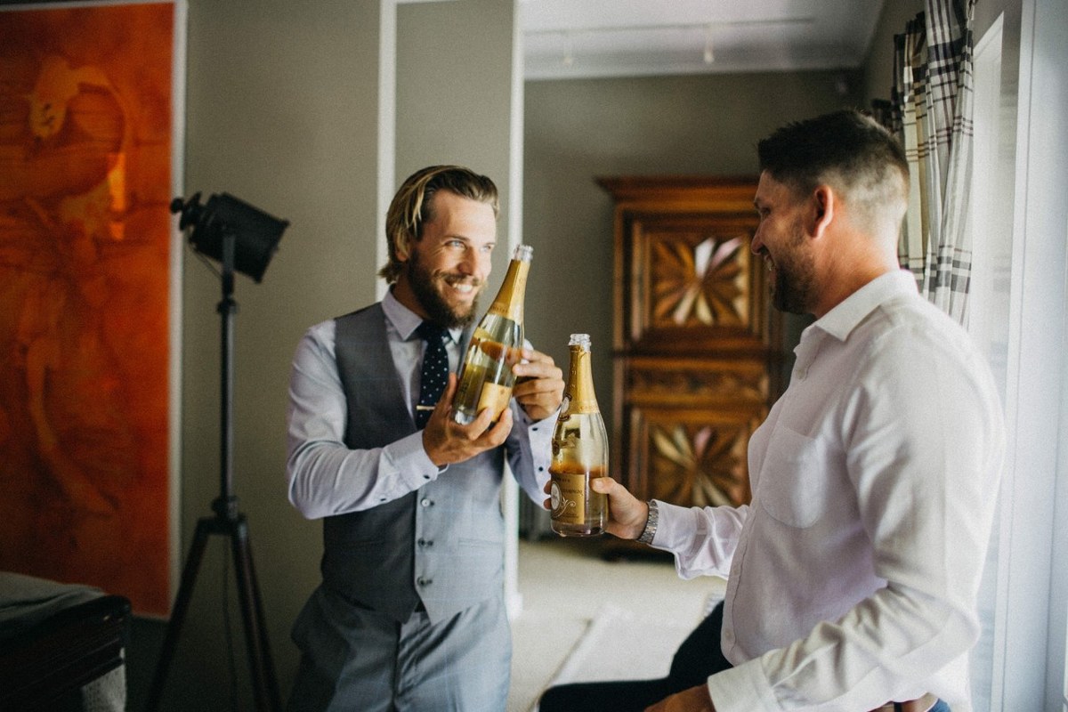 Groom dressing at Redleaf Wollombi — Joshua Mikhaiel, documentary wedding photographer The groom inspects his suit while an attendant adjusts his boutonniere. Photograph by documentary wedding photographer Joshua Mikhaiel.
