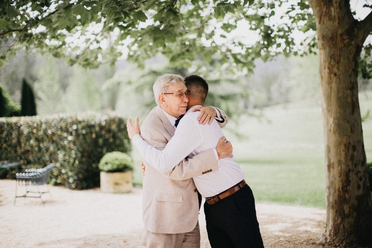 Groom greeting a guest at Redleaf Wollombi — Joshua Mikhaiel, documentary wedding photographer The groom embraces an older guest beneath the garden trees. Photograph by documentary wedding photographer Joshua Mikhaiel.