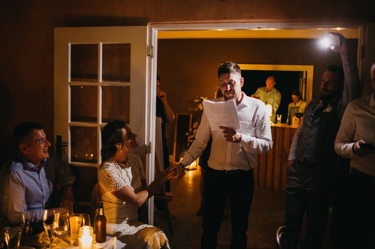 Wedding speech at Redleaf Wollombi — Joshua Mikhaiel, documentary wedding photographer A man speaks into a microphone while guests watch. Photograph by documentary wedding photographer Joshua Mikhaiel.