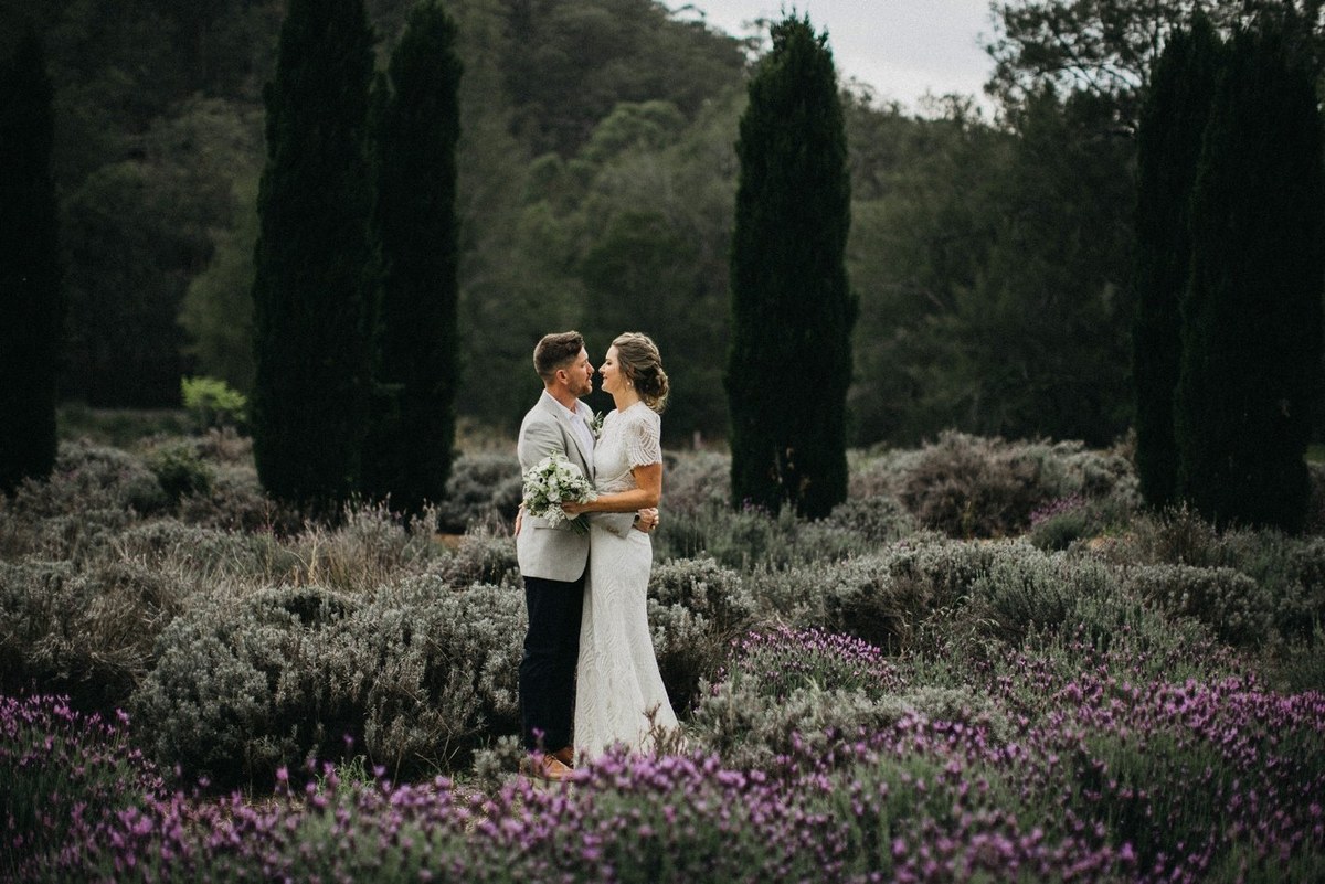 Newlyweds in the Redleaf gardens — Joshua Mikhaiel, documentary wedding photographer The bride and groom stand together among flowering shrubs and tall trees. Photograph by documentary wedding photographer Joshua Mikhaiel.