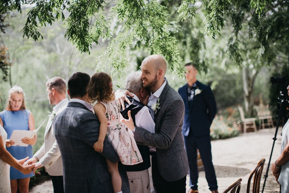 Bride greeting a guest at Redleaf Wollombi — Joshua Mikhaiel, documentary wedding photographer A guest embraces the bride beside the ceremony seating. Photograph by documentary wedding photographer Joshua Mikhaiel.