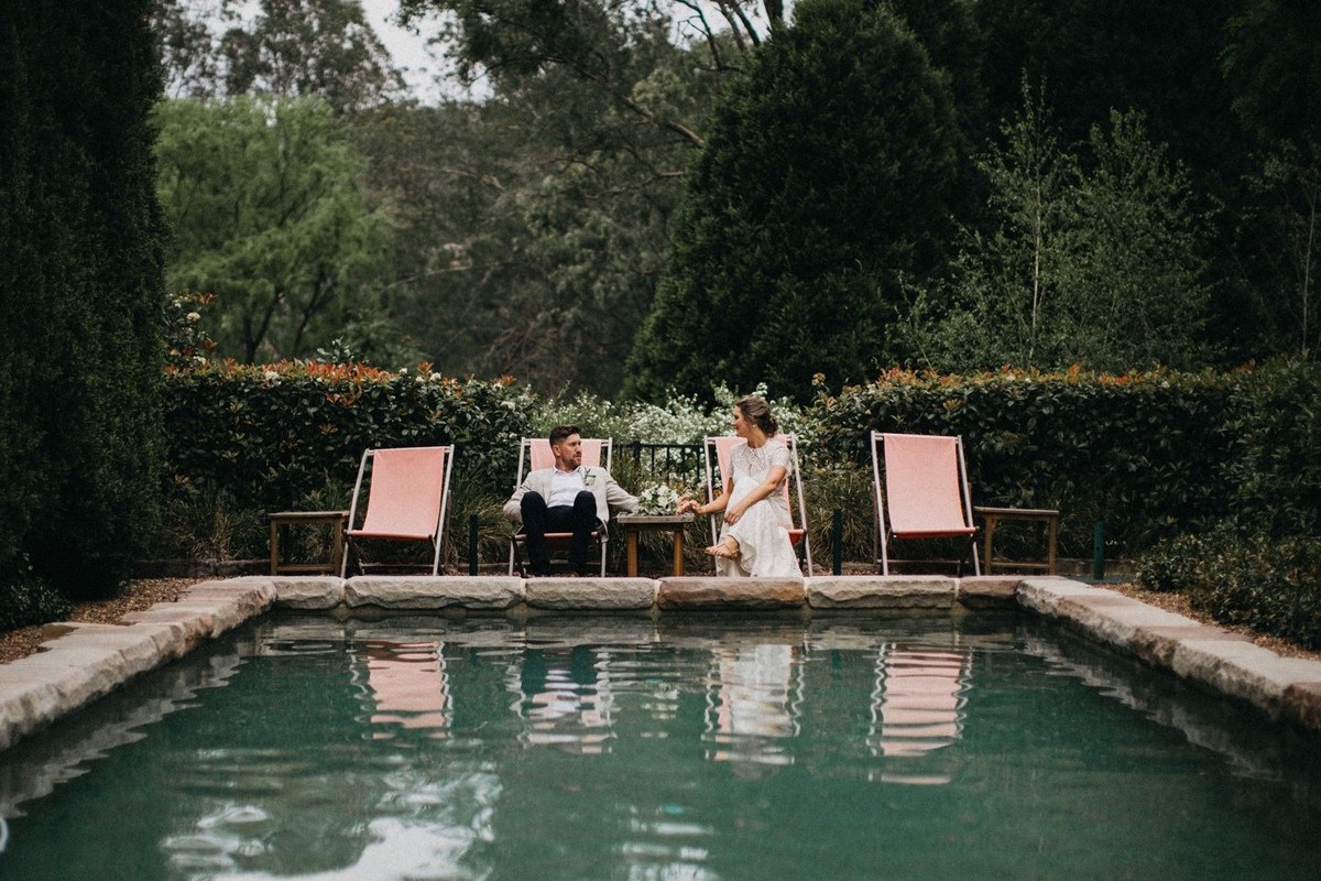 Newlyweds at Redleaf Wollombi — Joshua Mikhaiel, documentary wedding photographer The bride and groom sit together beside the swimming pool. Photograph by documentary wedding photographer Joshua Mikhaiel.