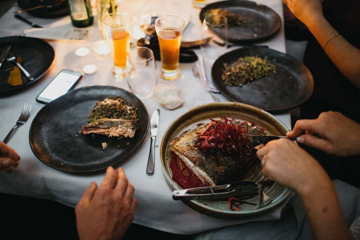 Wedding dinner at Redleaf Wollombi — Joshua Mikhaiel, documentary wedding photographer Guests eat and talk at candlelit tables in a two-photo collage. Photograph by documentary wedding photographer Joshua Mikhaiel.
