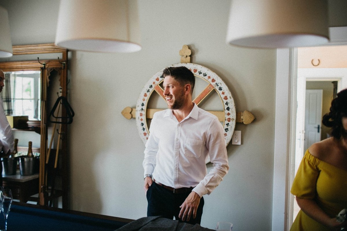 Groom preparing at Redleaf Wollombi — Joshua Mikhaiel, documentary wedding photographer The groom stands in the room beside a round mirror as he gets ready. Photograph by documentary wedding photographer Joshua Mikhaiel.