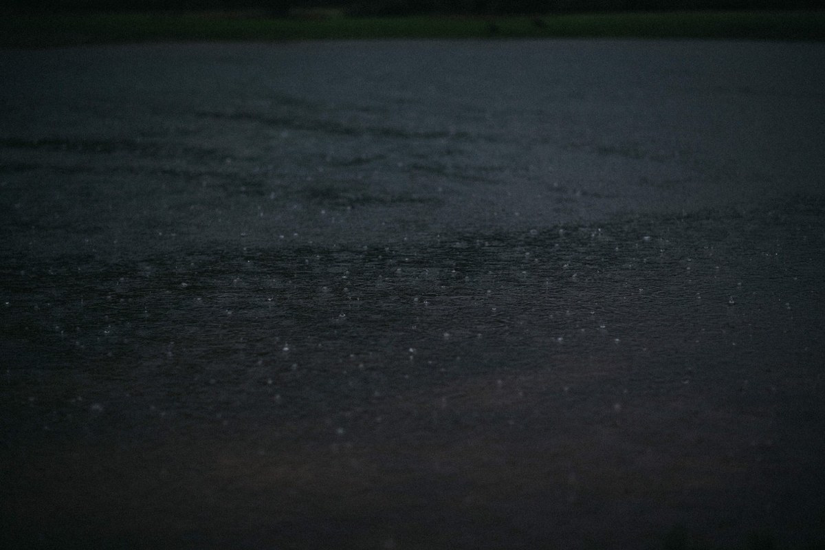 Rain falling at Redleaf Wollombi — Joshua Mikhaiel, documentary wedding photographer A dark water surface reflects faint light after the rain. Photograph by documentary wedding photographer Joshua Mikhaiel.