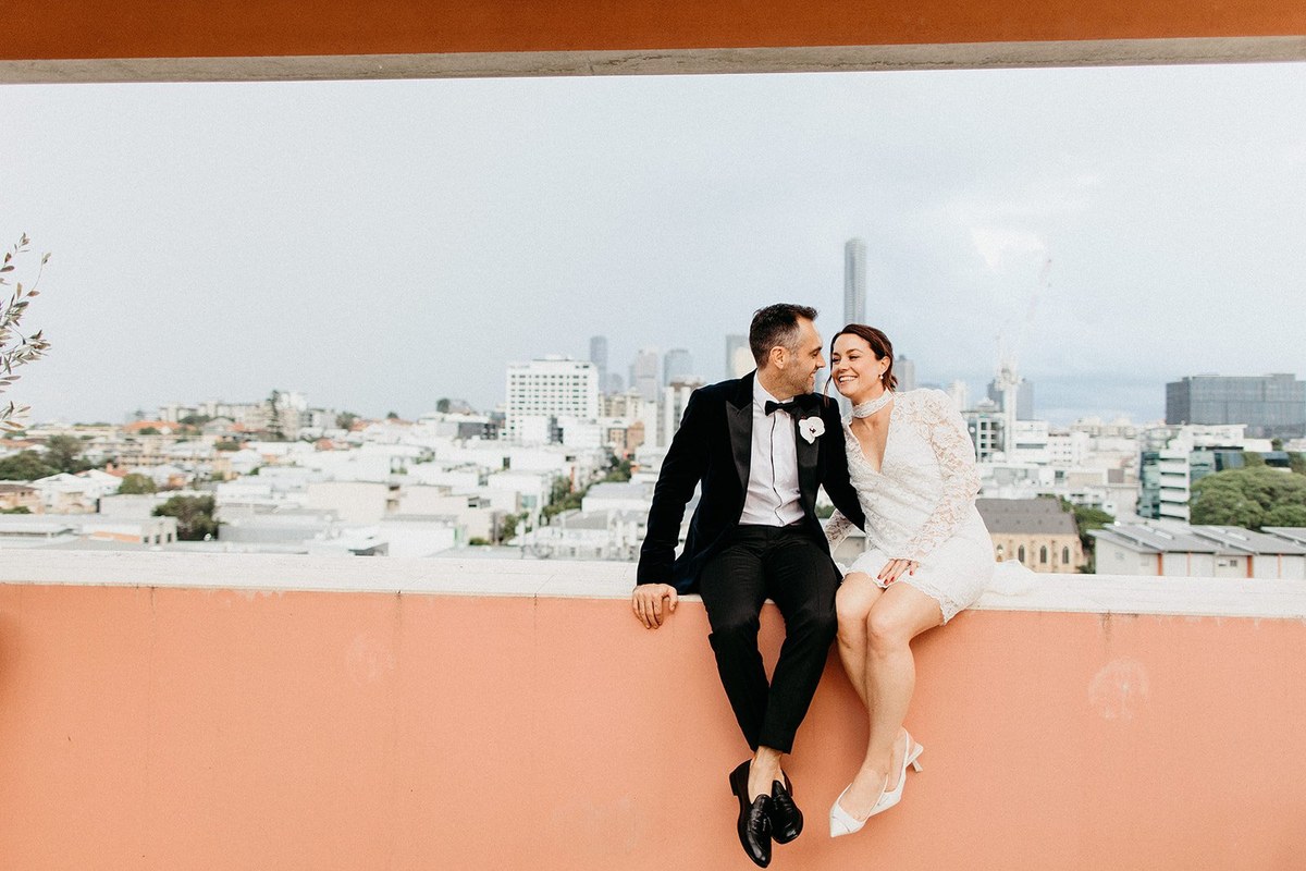 Calile Hotel elopement portrait — Joshua Mikhaiel, documentary wedding photographer A couple sit together on a peach-colored balcony overlooking the city. Photograph by documentary wedding photographer Joshua Mikhaiel.
