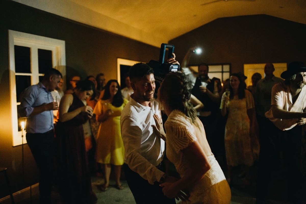 Guests playing a party game at Redleaf Wollombi — Joshua Mikhaiel, documentary wedding photographer A man holds a wooden bar while another guest ducks beneath it. Photograph by documentary wedding photographer Joshua Mikhaiel.