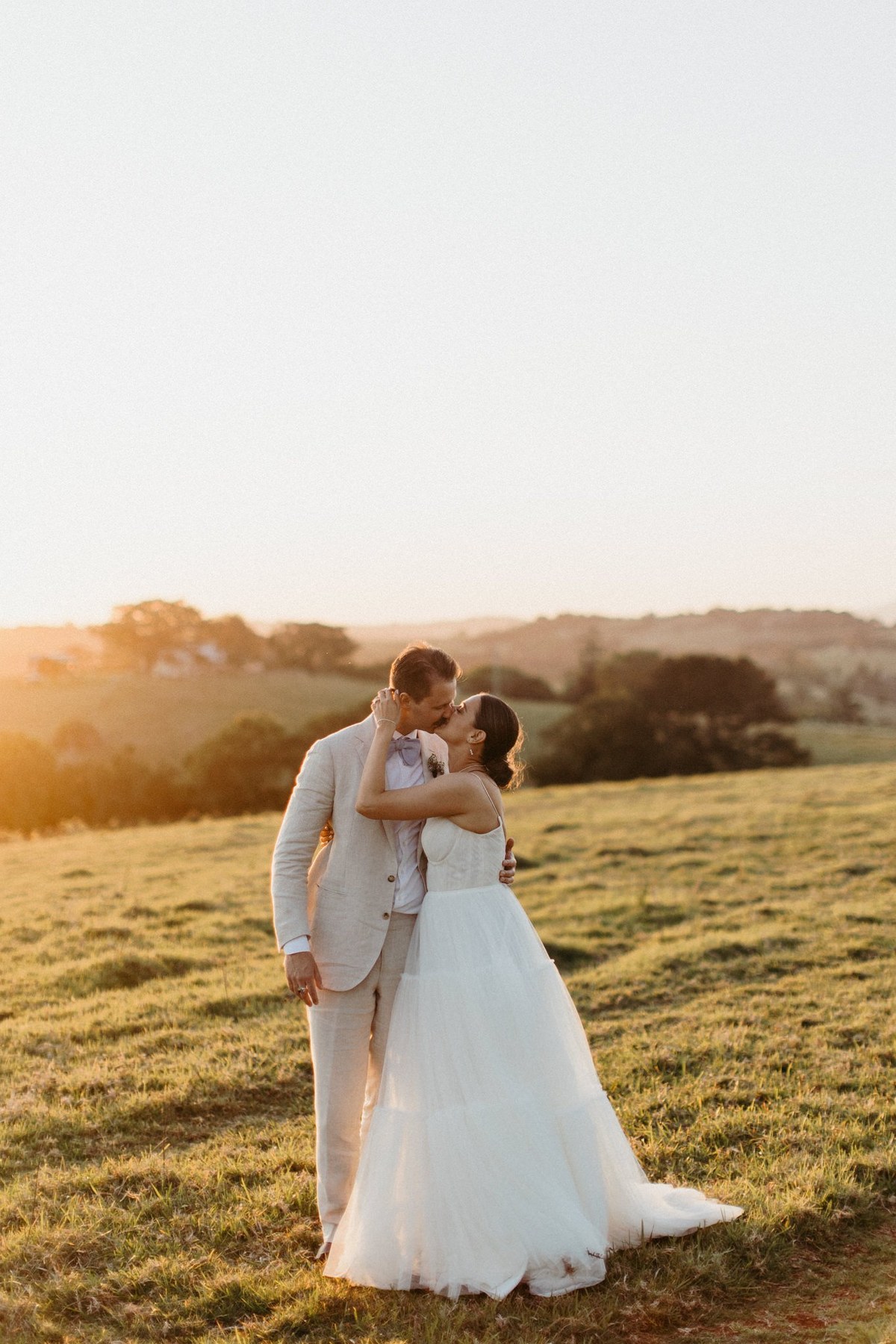 Wedding portraits at sunset — Joshua Mikhaiel, documentary wedding photographer A bride and groom embrace in a paddock in warm sunset light, photographed by documentary wedding photographer Joshua Mikhaiel.
